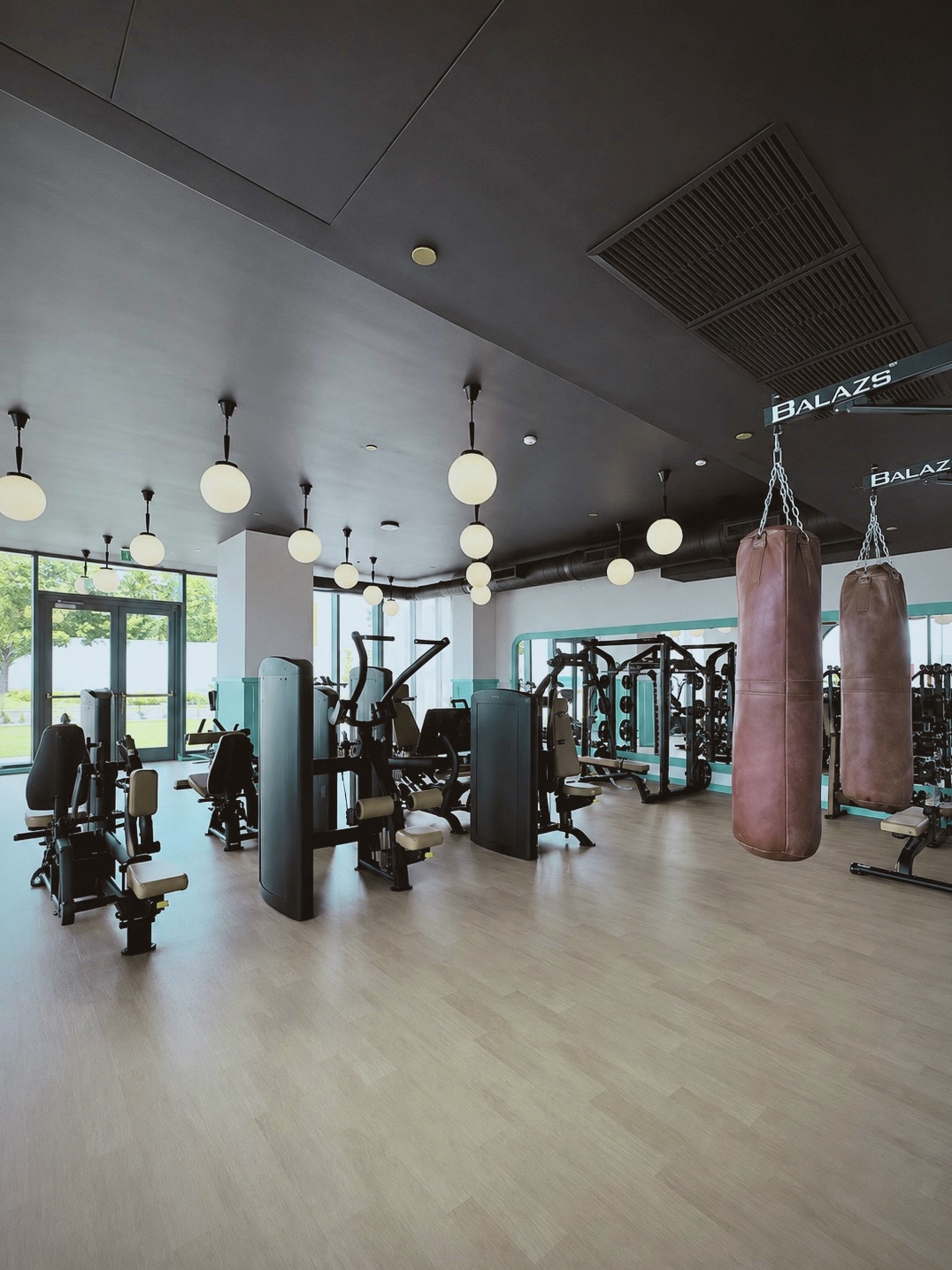 On-site fitness center with strength equipment, heavy bags, and globe pendants