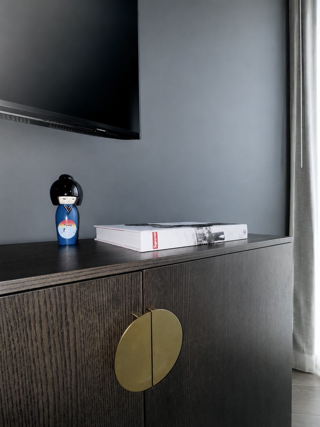 Detail of the dark oak credenza with brass hardware and art books