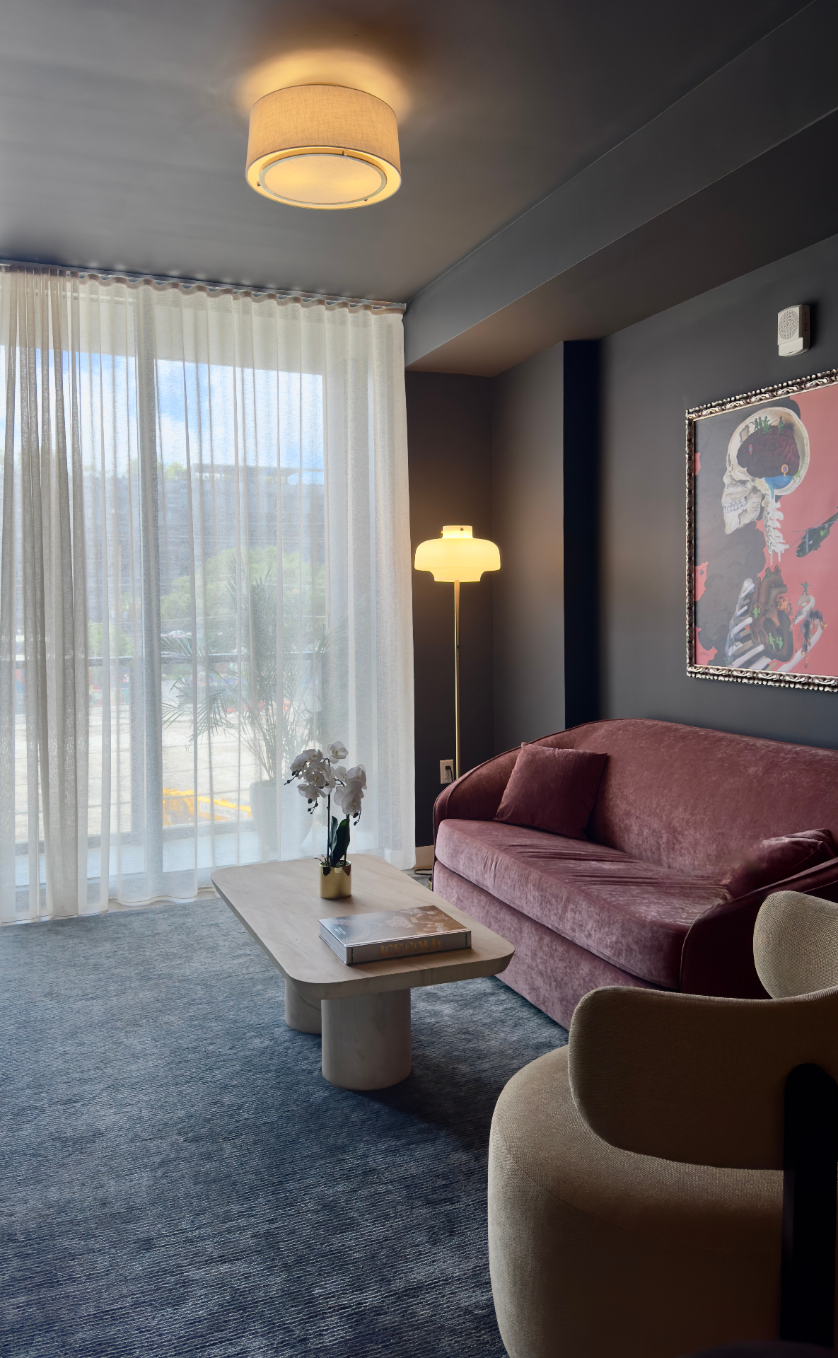 Pink velvet sofa under contemporary art with a floor lamp